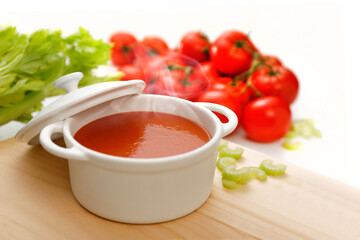 Frisch gekochte Tomatensuppe in weißer Keramik-Schalel mit Zutaten im Hintergrund / COPY SPACE