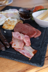 Traditional english breakfast on a plate. Baked eggs, halloumi, cheese ham and vegetables.