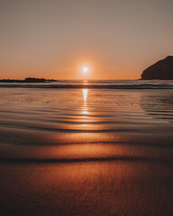 Sunset reflection on the warm beach sand by the ocean