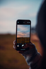 Taking a photo of sunset with phone in hand