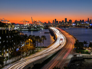 Fototapeta na wymiar Colorful sunset over Miami Downtown as seen from Miami Beach, long exposure of moving traffic over MacArthur Causeway, Florida, USA.