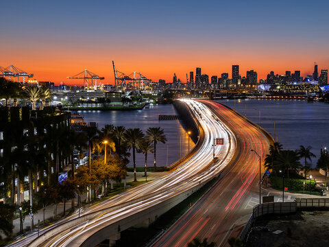 Colorful sunset over Miami Downtown as seen from Miami Beach, long exposure of moving traffic over MacArthur Causeway, Florida, USA.