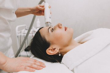 The cosmetologist makes the RF-lifting procedure for the client. Copy space. The concept of...