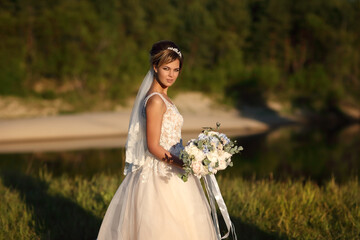 Fototapeta na wymiar bride with a bouquet of flowers on the background of the river. High quality photo