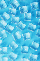 Many frosty and refreshing ice cubes with drops on a blue backgroun