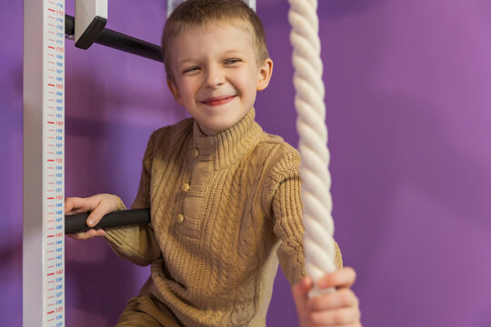 boy on the wall bars holding on to the rope