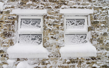 Windows and walls of an old stone house with snow and ice stuck to them (Weardale, North Pennines,...