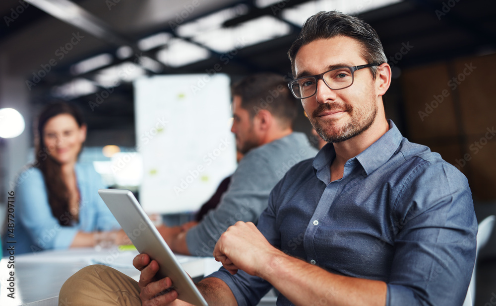 Poster the creative process. portrait of a man sitting at a table in an office using a digital tablet with 
