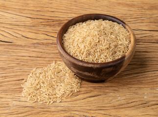 Raw brown whole rice in a bowl over wooden table