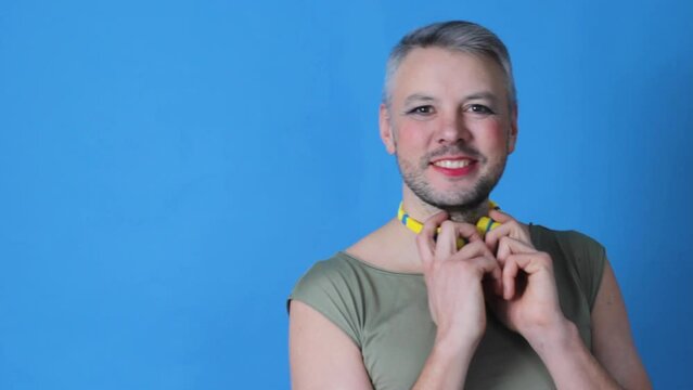 a gay man with makeup on his face moves slowly on a blue background. lgbt