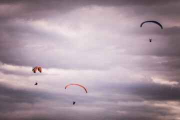 Paragliders flying, against a cloudy sky
