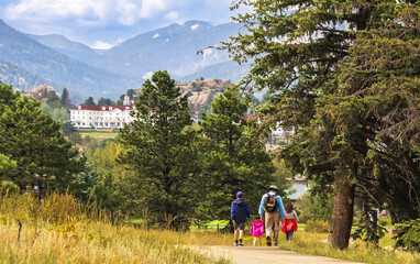 Three generations of family hiking near Estes Park, Colorado, in summer; building and mountains in background