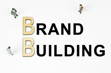 On a white background, figures of businessmen, wooden letters and the inscription - BRAND BUILDING