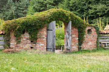 old wooden door leading to the garden, installed in a brick wall 