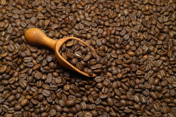 Coffee beans scattered close-up with a scoop.