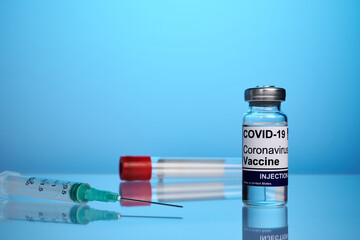 Covid vaccine set - labs photo on a blue background. Covid-19 remedy vial on a glass surface....