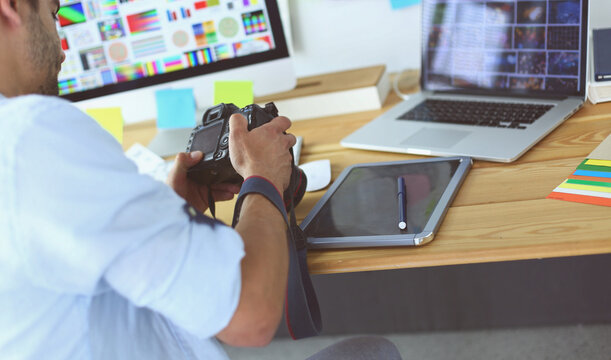 Portrait of young designer sitting at graphic studio in front of laptop and computer while working online