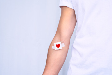 Blood donation concept with copy space. Blood donor with bandage after giving blood on a white...