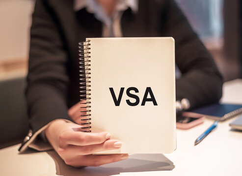 Businesswoman holding a white notepad with text VSA Volume Spread Analisys written on it