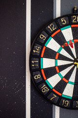 To hit the target with a dart, after failures. Ruined black and white wallpaper with holes from darts. Motivation to win. Holes in the wall and wallpaper from playing darts. Vertical photo.