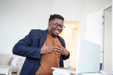 Naklejka premium Heart attack. Young businessman in sitting and and holding his chest because feeling pain on his heart. business and freelancing concept. indoor shot
