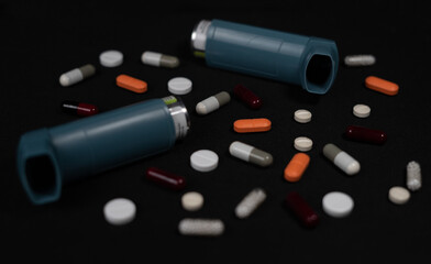 Multi-colored pills and inhaler on a table. Medicine for depression, fever, stomach pain.