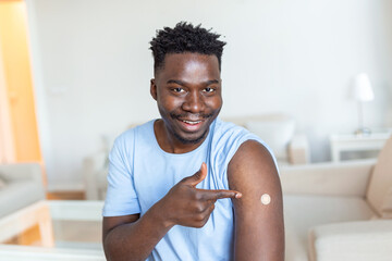 Portrait of a man smiling after getting a vaccine. African man holding down his shirt sleeve and...