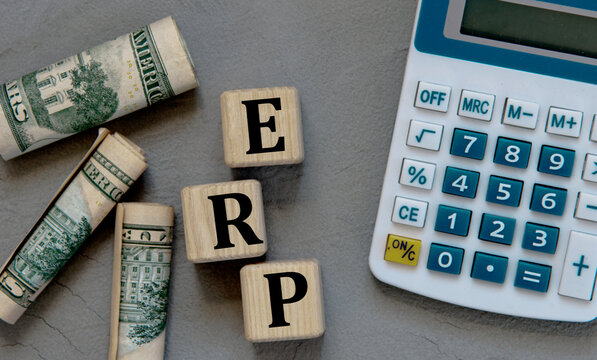 ERP - acronym on wooden cubes on a gray background with a calculator and banknotes.