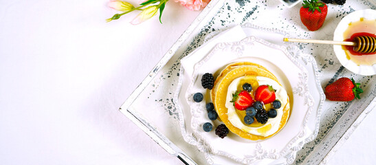 Pancake breakfast tray on table with syrup and blueberries fruit creative layout flat lay top view, with negative copy space. Sized to fit popular social media and web banner.