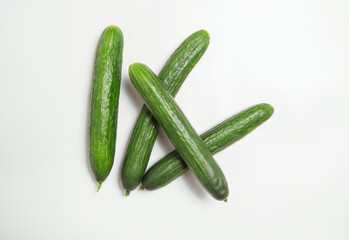 Four long green cucumbers crossways on white background