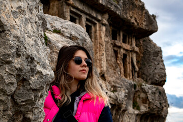 Tlos ancient city from Fethiye, Turkey. Young womanwith sun glasses is standing on ruins and looking around. Discover and travel concept. 