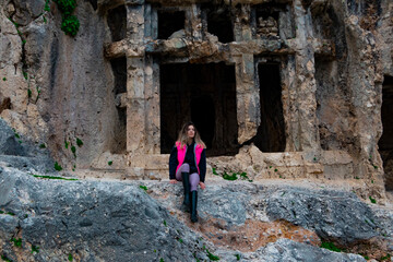 Tlos ancient city from Fethiye, Turkey. Young woman is sitting on rocks in front of  ruins. 