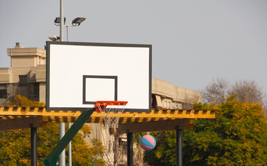 A basketball game, a ball flying into the net.Outdoors.