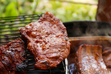 Marinated pork on the hot grill during a summer day. Barbecue party - crispy meat on the grill on the terrace.