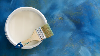  Top view of a jar with white paint on a blue background with light gilding. On top of the jar is a...