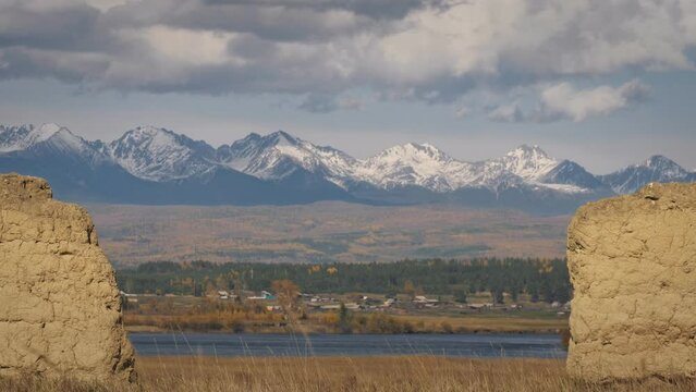 The man travel on mixed terrain cycle touring with bikepacking. The traveler journey with bicycle bags. Sport bikepacking, bike, sportswear in green black colors. Mountain snow capped, stone arch.