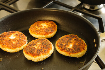 Cheesecakes in a frying pan during frying. The process of making curd fritters. selective focus