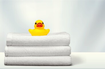A miniature bubble bath yellow rubber duck and towels on the bathroom