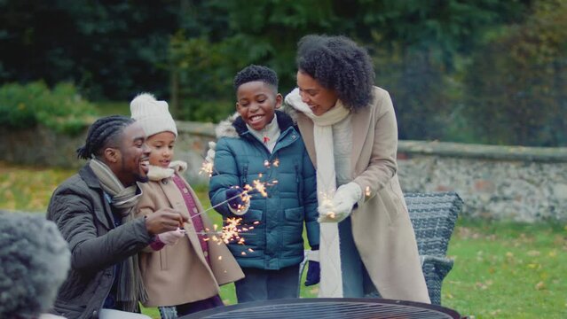 Family having fun with sparklers in autumn garden at home - shot in slow motion