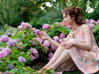 Portrait of young Asian woman sitting in colorful hydrangea flower forest, beautiful Chinese girl in colorful dress enjoy peaceful life in forest park.