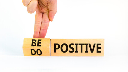 Be and do positive symbol. Businessman turns wooden cubes and changes words be positive to do positive. Beautiful white background. Business, be and do positive concept. Copy space.