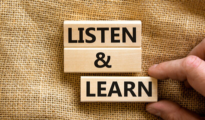 Listen and learn symbol. Concept words Listen and learn on wooden blocks. Beautiful canvas table canvas background. Businessman hand. Copy space. Business, educational and listen and learn concept.