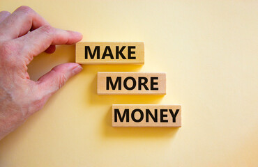 Make more money symbol. Concept words Make more money on blocks on beautiful white table white background. Businessman hand. Business and make more money concept. Copy space.