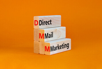 DMM direct mail marketing symbol. Concept words DMM direct mail marketing on blocks on a orange table, orange background. Business and DMM direct mail marketing concept. Copy space.