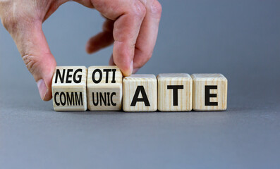 Negotiate and communicate symbol. Businessman turns cubes and changes the word communicate to negotiate. Beautiful grey background. Business negotiate and communicate concept. Copy space.