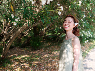 Portrait of young Asian woman standing in white oleander flower forest background, beautiful...