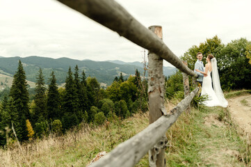Fototapeta na wymiar Beautiful newlyweds hug and smile being in nature. Portrait of the bride and groom in a lace dress. Wedding day of a happy couple of newlyweds. couple in the mountains