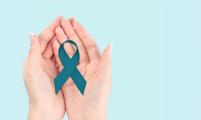 Teal awareness ribbon awareness for Ovarian Cancer month, hand with ribbon