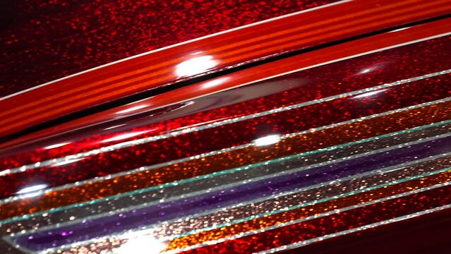 This panning video shows a close up view of a sparkling metal flake red lowrider custom paint job.