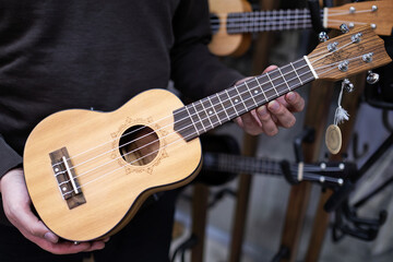 Obraz na płótnie Canvas Music store salesman showing a ukulele guitar